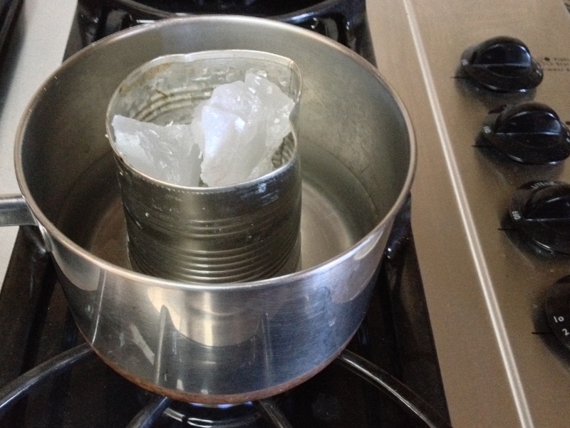 Melting wax using a double boiler of a used tin can with spout in a pan with boiling water. #TexasHomesteader