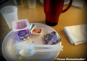 Disposable trash from a hotel breakfast including styrofoam plates, plastic fork and spoon, plastic tub of yogurt and plastic tub of jelly. Staying at a hotel with a free breakfast creates lots of waste. UNTIL I discovered easy ways to keep my low-waste convictions. #TexasHomesteader